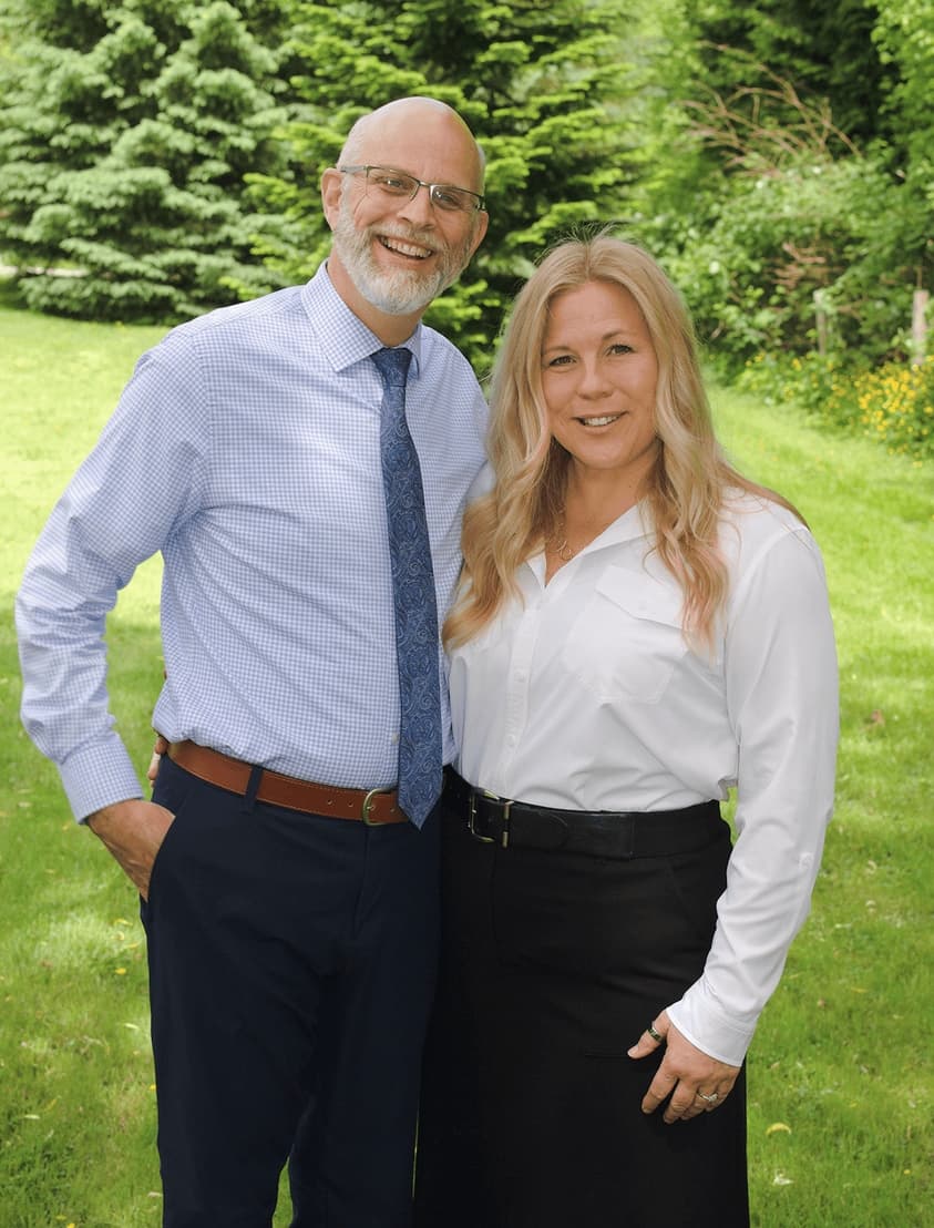 An image of Alayne Janzen standing in front of a willow tree, with her hands crossed.